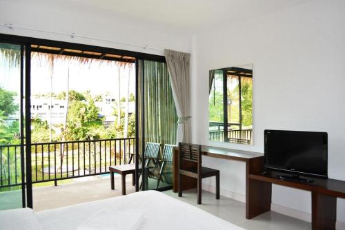 a bedroom with a bed and a television and a balcony at The Nidhra Boutique Resort in Baan Tai