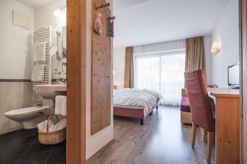 ein Bad mit einem Waschbecken und ein Bett in einem Zimmer in der Unterkunft Hotel Innerhofer in Gais