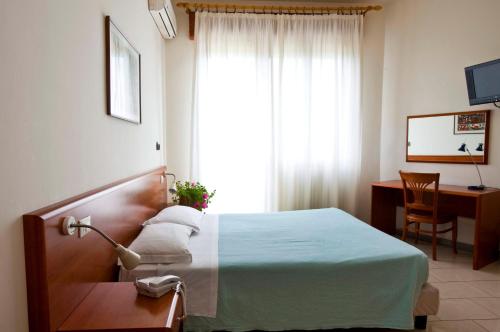 a bedroom with a bed and a desk and a window at Hotel Adriatico in Borgo Fosso Ghiaia