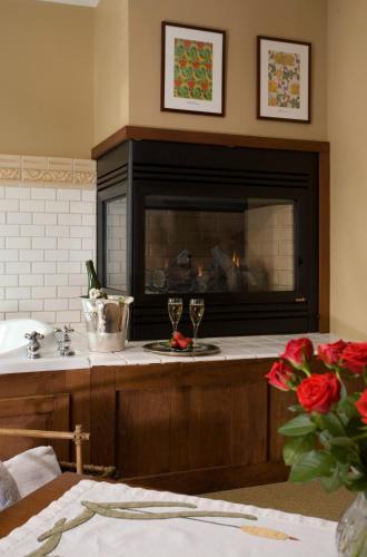 a kitchen with a fireplace and two glasses of wine at Lake Pointe Inn in McHenry