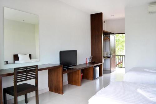 a hotel room with a bed and a tv at The Nidhra Boutique Resort in Ban Tai