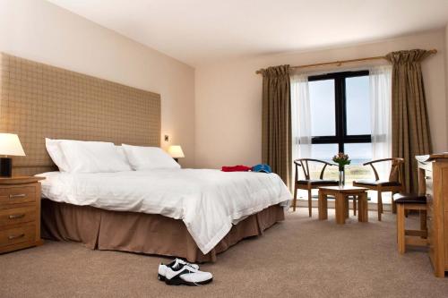 AberladyにあるThe Lodge at Craigielaw and Golf Coursesのベッド、テーブル、椅子が備わるホテルルームです。