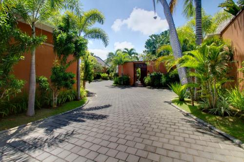a cobblestone driveway in front of a house with palm trees at The Kunja Villa-Hotel in Seminyak