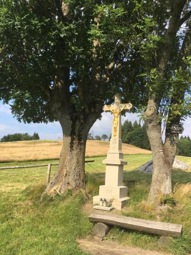 a cross in a field next to two trees at Chaty Pohoda na Soláni in Velké Karlovice