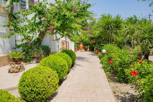 a walkway in a garden with bushes and flowers at Paul's Garden Studios in Haraki