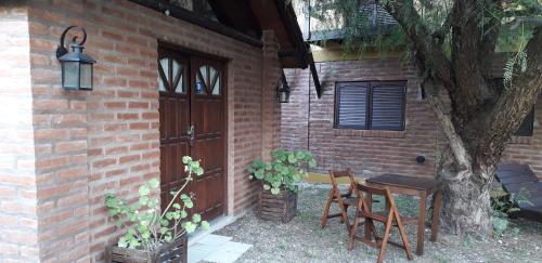una casa de ladrillo con mesa y sillas junto a un árbol en Clima Serrano en Merlo