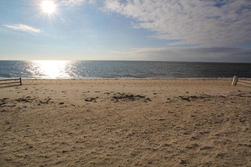 a sandy beach with the sun and the ocean at Ocean Club on Smuggler's Beach in South Yarmouth