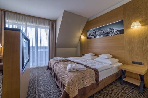 a hotel room with a bed and a television at Grand Nosalowy Dwór in Zakopane