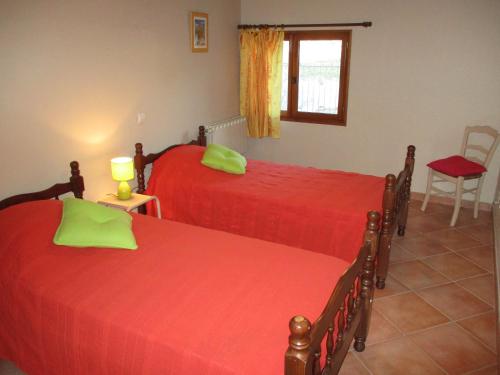 - une chambre avec 2 lits avec des draps rouges et une fenêtre dans l'établissement Gîte en provence au coeur des vignes, à Villedieu