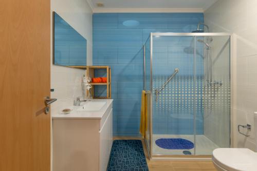 a blue bathroom with a shower and a sink at Vivenda Golfinho Barra in Praia da Barra