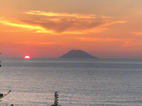 a sunset over the ocean with a mountain in the distance at Hotel La Fattoria Sul Mare in Capo Vaticano