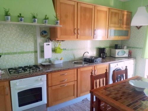 a kitchen with wooden cabinets and a stove and a table at Casa do Mar - Nazaré in Nazaré