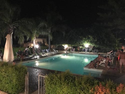 a swimming pool at night with people sitting around it at Hotel La Fattoria Sul Mare in Capo Vaticano