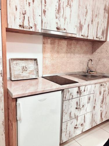 a kitchen with white wooden cabinets and a sink at J&B - Beachside Studio Apartment in Makarska