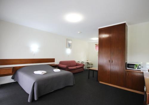 Habitación de hotel con cama y silla en Melaleuca Lodge Beaconsfield, en Beaconsfield