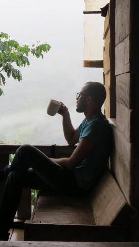 a man sitting on a window sill drinking a cup of coffee at EYA Ecolodge in San Isidro