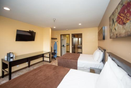a hotel room with two beds and a desk at Casa Bella Inn- Huntington Park in Huntington Park