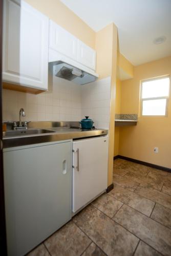 a kitchen with white cabinets and a sink at Casa Bella Inn- Huntington Park in Huntington Park