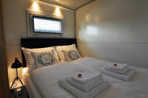 Un dormitorio con una cama blanca con toallas. en Cozy floating boatlodge "Het Vrijthof" en Maastricht