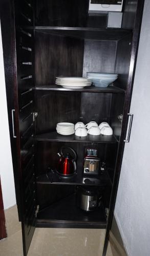 a black cabinet with plates and dishes on it at Holiday Hire Fiji in Lautoka