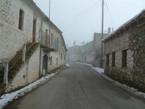 an empty street in an old town in the snow at Varnous Hotel in Agios Germanos