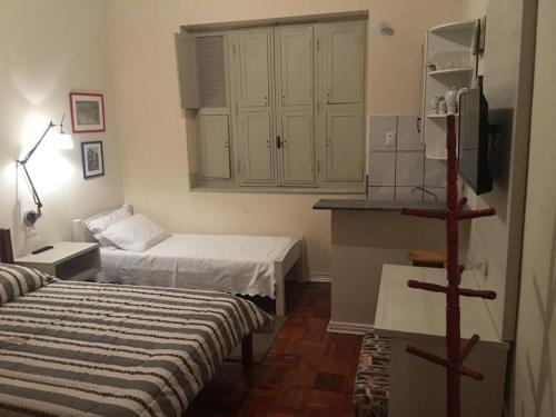 une petite chambre avec deux lits et une cuisine dans l'établissement Apts no Condominio Quisisana, à Poços de Caldas