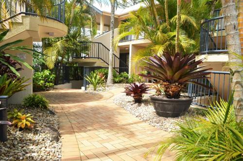 a walkway in front of a building with palm trees at Outrigger Bay in Byron Bay