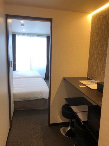 a hotel room with a bed and a desk and a mirror at UU Inn Kyoto in Kyoto