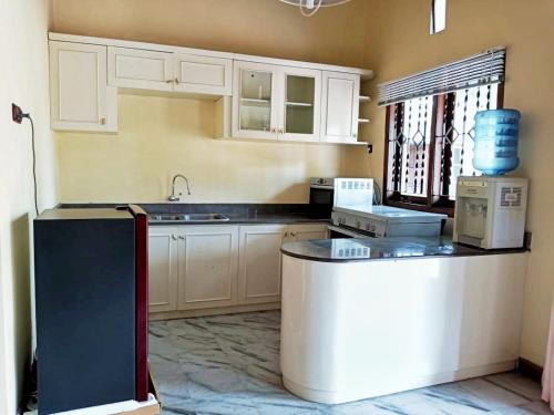 a kitchen with white cabinets and a black counter top at The Terrace House in Denpasar