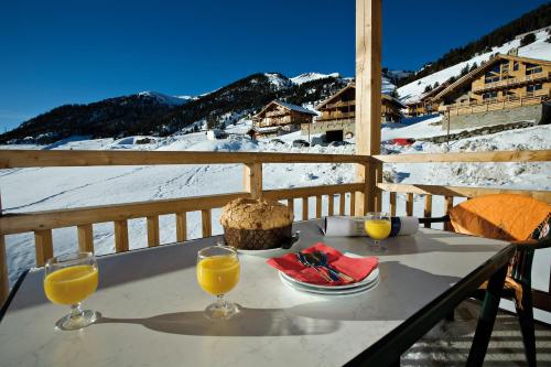 a table with a plate of food and two glasses of orange juice at Résidence Club mmv Le Hameau des Airelles **** in Montgenèvre
