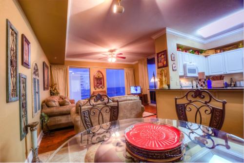 a kitchen and a living room with a glass table at Tidewater Beach Resort 1818 By Aneliya in Panama City Beach