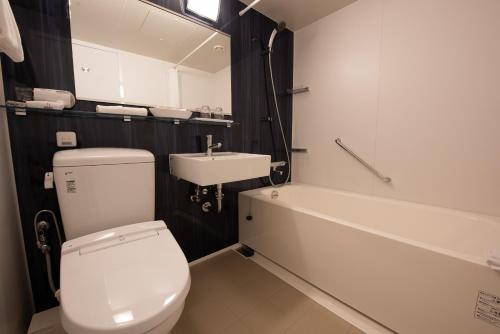 a bathroom with a toilet and a sink and a tub at Hotel Hewitt Koshien in Nishinomiya