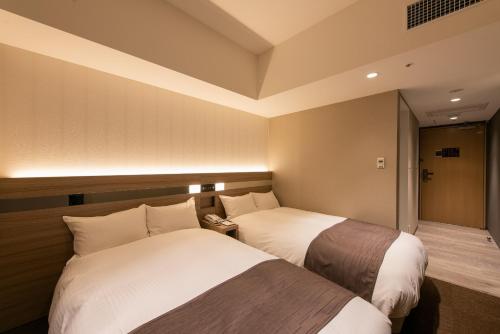a hotel room with two beds in a room at Hotel Hewitt Koshien in Nishinomiya
