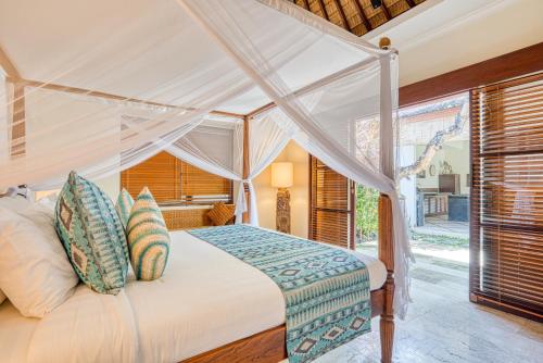 a bedroom with a canopy bed with a window at VILLA AISHA in Sanur