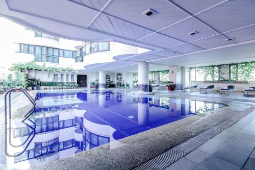 uma grande piscina num edifício com mesas e cadeiras em Makati Palace Hotel em Manilla