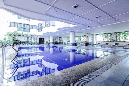 a large pool in a building with tables and chairs at Makati Palace Hotel in Manila