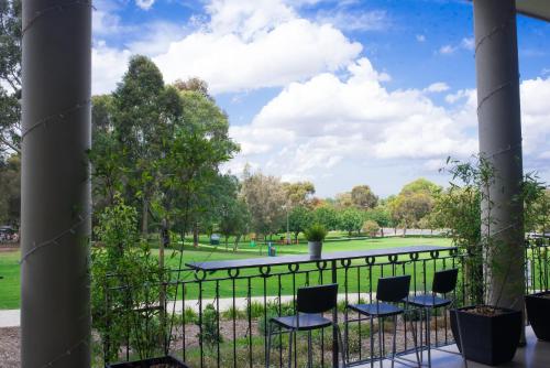 a view of a park from a balcony with chairs at Sfera's Park Suites & Convention Centre in Adelaide