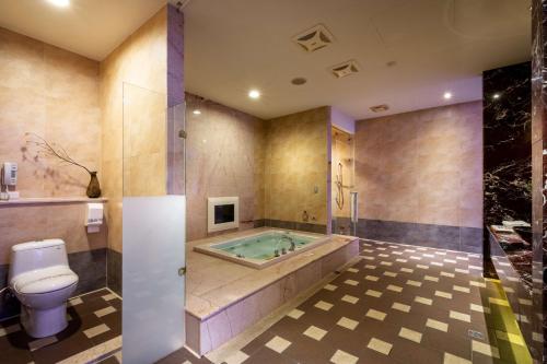 a bathroom with a tub and a toilet and a bath tub at Vogue Boutique Motel in Yangmei