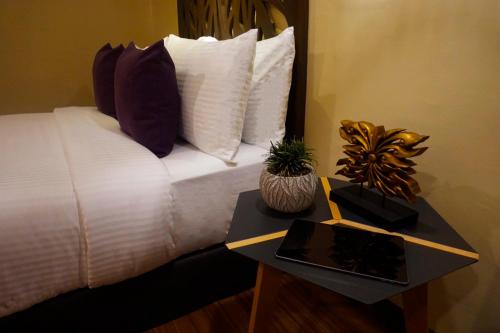a bed with pillows and a table with a tablet at Balai Princesa in Puerto Princesa City