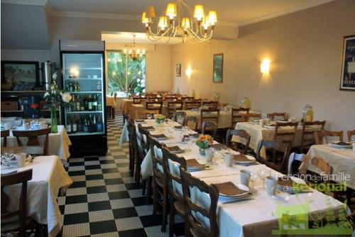 a restaurant with tables and chairs and a chandelier at Pension de Kerioual in Roscoff