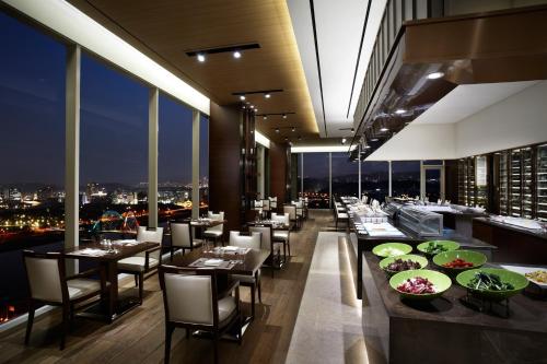 a restaurant with tables and chairs and a view of the city at LOTTE City Hotel Daejeon in Daejeon