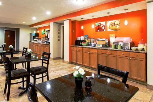 a restaurant with tables and a kitchen with orange walls at Quality Inn Plainfield I-395 in Plainfield
