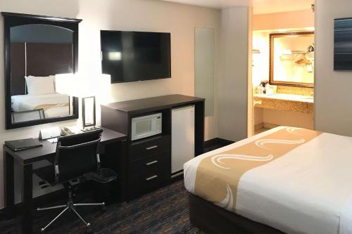 a hotel room with a bed and a desk with a computer at Quality Inn Ontario Airport Convention Center in Ontario