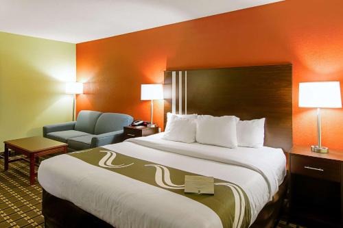 a hotel room with a large bed and a chair at Quality Inn Plainfield I-395 in Plainfield