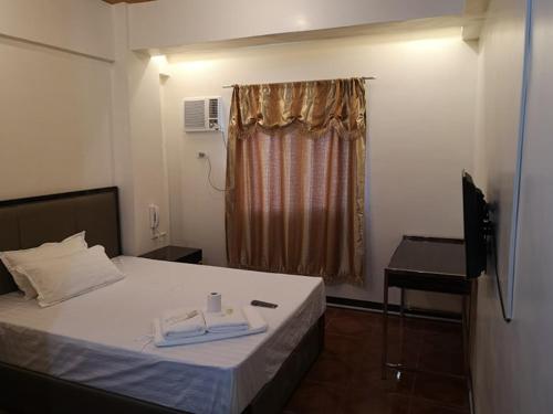 a bedroom with a bed and a chair and a window at Meaco Royal Hotel - Malabon in Manila