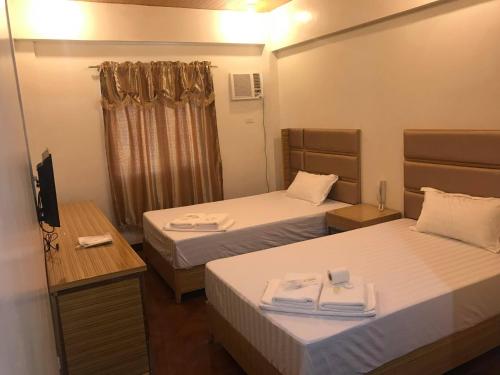a hotel room with two beds and a television at Meaco Royal Hotel - Malabon in Manila