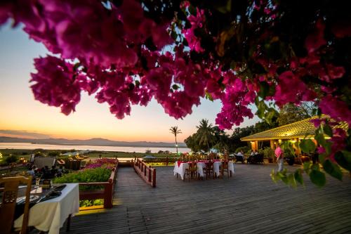 a deck with tables and chairs and pink flowers at Bagan Thiripyitsaya Sanctuary Resort in Bagan