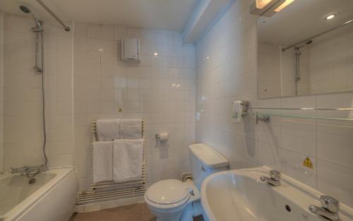 a bathroom with a toilet and a tub and a sink at The Elms Hotel in East Retford