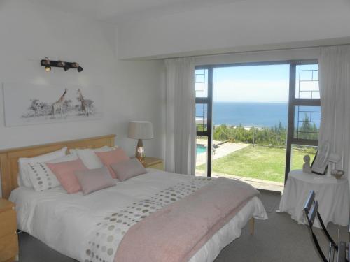 a bedroom with a bed with a view of the ocean at Whale Views in Gordonʼs Bay