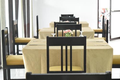 a set of tables with chairs and a vase of flowers at Jambura Inn in Gorontalo